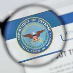 Magnifying glass over Department of Defense logo.
