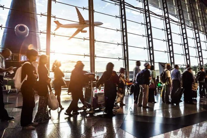 Crowd of travelers in airport terminal with airplane outside.