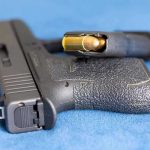 Army Romance Turns DEADLY at Base Handgun on blue fabric with visible bullet cartridge.