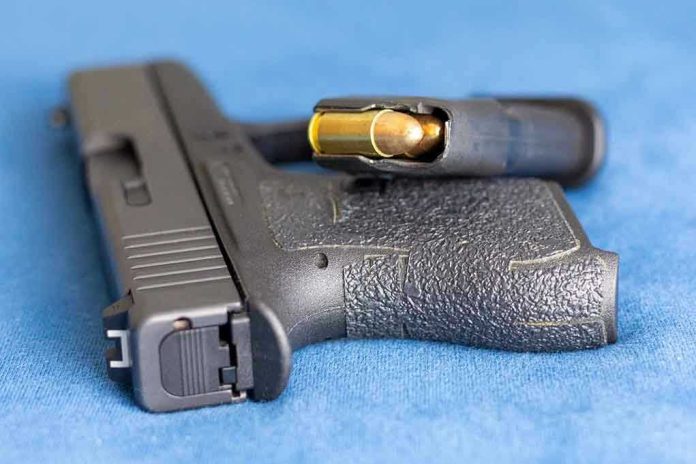 2159542825 Handgun on blue fabric with visible bullet cartridge.