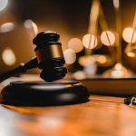 Grammy Star Faces Gavel: Could End it All Gavel on wooden table with scales in background.