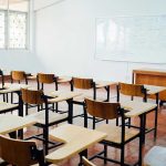 Empty classroom with desks, chairs, and whiteboard.