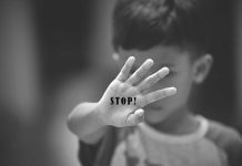 Child holding up hand with "STOP!" written on palm.