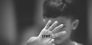 Child holding up hand with "STOP!" written on palm.
