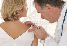 Doctor examining a patient's skin with a magnifying glass
