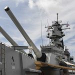 Close up of a battleships naval guns and superstructure against a cloudy sky