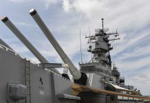 Close up of a battleships naval guns and superstructure against a cloudy sky
