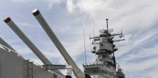 Close up of a battleships naval guns and superstructure against a cloudy sky