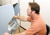 A man using an electronic voting machine in a privacy booth