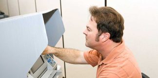 A man using an electronic voting machine in a privacy booth