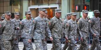 Group of soldiers marching in a military parade on a city street