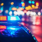 BRUTAL Attack Rocks Police Force – Officer Slain! Police car with flashing lights at night.