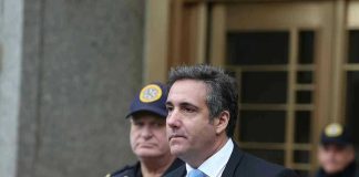 Man in suit walking outside with security officers.