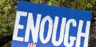 Person holding sign that says Enough outdoors