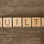 Wooden blocks arranged to spell 'GUILTY' on a wooden surface