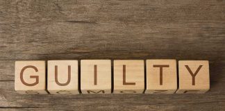 Wooden blocks arranged to spell 'GUILTY' on a wooden surface