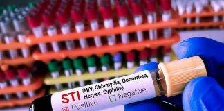 Gloved hand holding STI test tube labeled Negative.