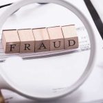Fraud blocks under magnifying glass on invoices.