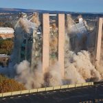 A building being demolished with dust and debris in the air