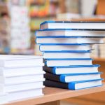 A stack of neatly arranged books on a wooden table in a bookstore