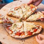 People sharing slices of pizza on a wooden board