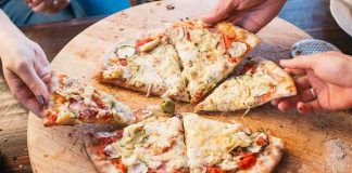 People sharing slices of pizza on a wooden board