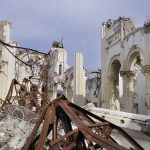 Interior view of a destroyed building with collapsed arches and debris