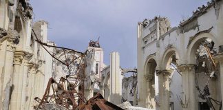 Interior view of a destroyed building with collapsed arches and debris