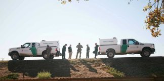 Border Patrol vehicles and agents on a ridge.