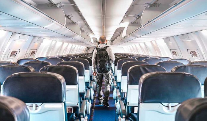Person walking down empty airplane aisle