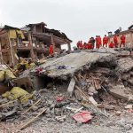 Rescue workers in orange uniforms on a collapsed building site after an earthquake