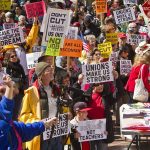 Crowd of protesters holding signs advocating for labor rights and social justice