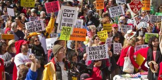 Crowd of protesters holding signs advocating for labor rights and social justice