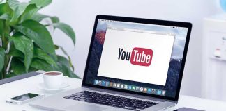 Laptop displaying YouTube, with coffee and stationery nearby.