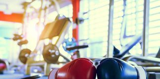 Boxing gloves on gym floor with equipment.