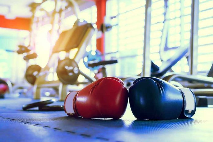 Boxing gloves on gym floor with equipment.