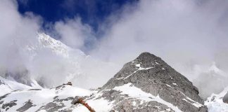 Snow-covered mountain with hiking trails and tourists under a cloudy sky