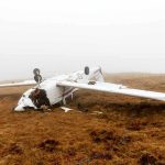 Crashed airplane lying on its side in a foggy field