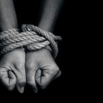 Two hands tightly bound with rope against a dark background