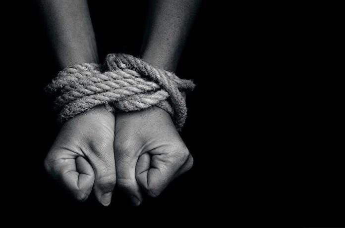 Two hands tightly bound with rope against a dark background