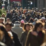 A crowded urban street filled with pedestrians walking in various directions