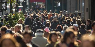 A crowded urban street filled with pedestrians walking in various directions