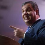 A man in a suit passionately speaking at a podium