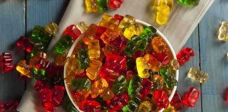 A bowl filled with colorful gummy bears surrounded by scattered candies