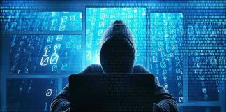 Person in hoodie using a laptop with digital code.