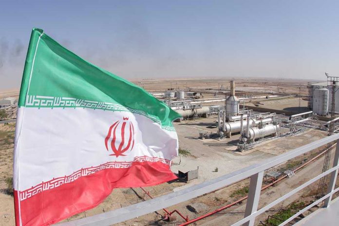 Iranian flag near an industrial gas refinery.