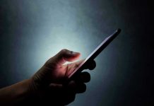 Sweden’s Phone Crackdown Shocks Parents Hand holding a smartphone in the dark.