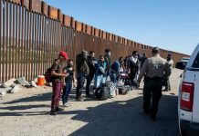 Border patrol agents interact with a group of people.