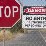 Stop and Danger signs on a chain-link fence.