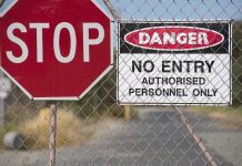 Stop and Danger signs on a chain-link fence.